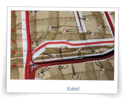 Für das Infozentrum der Zeche Friedrich-Heinrich in Kamp-Lintfort habe ich dieses Modell gefertigt. Das Modell zeigt das Zechengelände mit einem dazugehörigen Panel, dessen Knöpfe jeweils kleine LEDs aktivieren, und den Besucher interaktiv das ehemalige Zechengeände erkunden lässt. Hier die Verkabelung des Modells. Diese Verkabelung ist ein schönes Beispiel für unsere Arbeitsweise: Die Kabel wird sicherlich niemand je wieder zu Gesicht bekommen. Trotzdem legen wir Wert darauf, dass die Kabel ordentlich verlegt sind. Hier wurden die Kabel erst mit doppelseitigem Klebeband auf die Grundplatte einzeln und nacheinander geklebt, anschließend wurden die Kabel per abdeckendem Klebeband fixiert. Dadurch erreicht man eine nachvollziehbare Ordnung. Auch wenn es niemand je wieder sehen wird: Uns ist das wichtig. Es werden bei diesem Modell diverse LEDs per Knopf aktiviert. Eine extra Schaltung mittels Arduino braucht man dafür allerdings nicht. Eine einfache 9V-Blockbatterie reicht vollkommen aus.