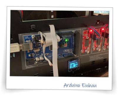 Wenn ein Modell Elektronik-Komponenten besitzt, macht es mir immer große Freude, diese Komponenten sauber einzubauen. Das ist zwar eigentlich gar nicht nötig, denn man sieht die Bauteile ohnehin nicht, aber es macht einfach einen besseren Eindruck, wenn auch die Steuerungselektronik gut aussieht. So verwenden wir für die Verkabelung der Elektronik wenn möglich Flachbandkabel, die auf die exakte Länge gekürzt werden, und an die Kabelenden werden DuPond-Stecker gekrimpt, damit diese Stecker wieder auf die Buchsen der Elektronik-Komponenten passen. Ein Klebestreifen zum Abschluss sichert die Stecker gegen das herausrutschen. 
Im unteren Bereich auf dem Bild ist ein kleiner Debug-Monitor zu sehen. Dieser zeigt im Klartext an, welchen Zustand welche Variable aktuell besitzt bzw. gibt Statusmeldungen u. ä. Sehr praktisch bei der Fehlersuche.
